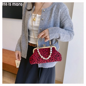 Close-up of red leopard print shell bag with pearl handle and golden clasp closure