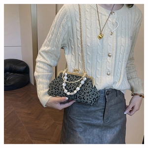 Leopard print shell handbag with bead handle and gold chain strap on beige knit sweater