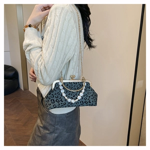 Detail of leopard print shell bag with golden metal frame and pearl beaded handle