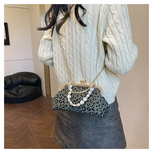 Detailed view of leopard print shell bag with gold chain and beaded handle on model