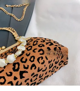 Detailed shot of leopard print handbag featuring shell-shaped bead handle and gold chain