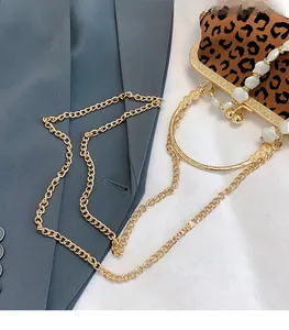 Macro shot of high-shine gold chain strap with leopard print bag and pearl handle