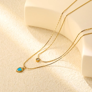 Détail du collier double couche plaqué or 18 carats avec pendentif coeur et pierre bleue