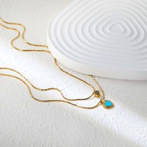 Détail d'un collier double épaisseur plaqué or 18 carats avec cœur bleu et pendentif zircon