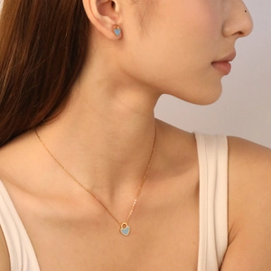Primo piano di una collana con ciondolo a cuore azzurro e set di orecchini dorati abbinati