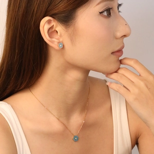 Set di collana e orecchini dorati con fiori blu indossati da una modella asiatica