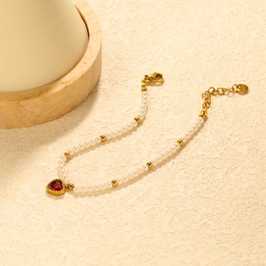 Macro detail of pearl bracelet featuring red heart zircon and gold-plated adjustable clasp