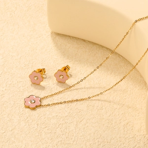 Dettaglio del set di gioielli dorati con fiori in smalto rosa e piccoli cristalli