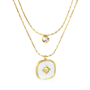 Layered gold necklace with square starburst pendant and white inlay on a white background