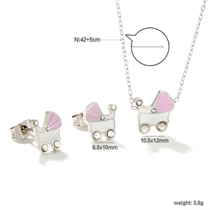 Dettaglio di un set di gioielli a forma di passeggino in smalto rosa e bianco con cristalli