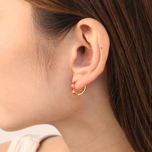 Detail of bamboo style hoop earring with red enamel and crystals on a female model