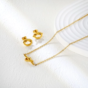 Parure bijoux nœud doré minimaliste avec collier et boucles d'oreilles sur plateau blanc