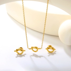 Ensemble bijoux nœud doré avec collier et boucles d'oreilles sur présentoir blanc