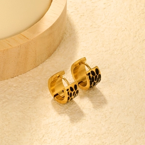 Detailed close-up of golden bamboo earrings with leopard print enamel on textured surface