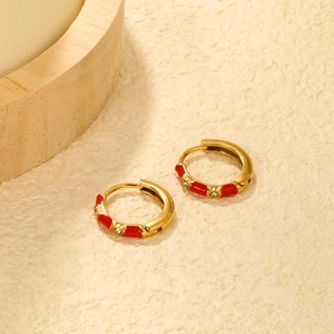 Detail of gold bamboo huggie earrings with red enamel and inlaid cubic zirconia crystals