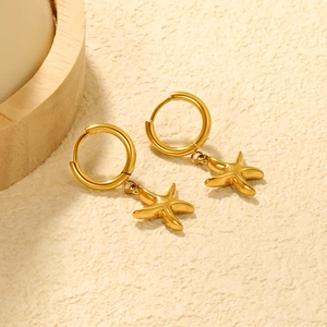 Detailed close-up of 18K gold plated stainless steel starfish hoop earrings on cream surface