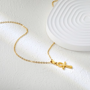 Polished 18K gold plated stainless steel Ankh cross necklace on a white stone background