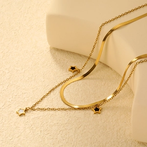 Collier double rang doré avec pendentifs étoiles et chaîne serpent sur fond beige texturé