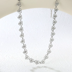 Detail of silver heart-shaped necklace featuring sunburst texture and lobster clasp