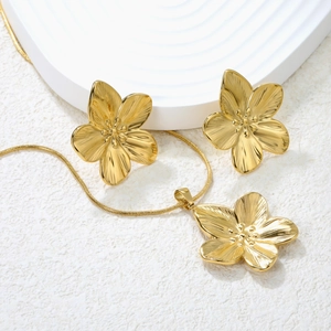 Detail of gold flower jewelry set with textured petals and snake chain necklace