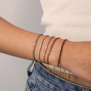 Set mit fünf goldenen Edelstahl-Tennisarmbändern mit bunten Zirkoniasteinen am Handgelenk