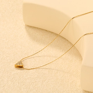 Élégant collier cœur évidé doré avec cristaux sur un fond beige minimaliste chic