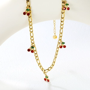 Detail of 18K gold plated chain necklace featuring red cherry pendants with green crystals
