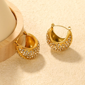 Luxurious gold-plated C-shaped hoop earrings with shimmering white rhinestones on beige surface