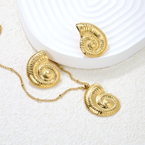 Macro view of gold nautilus shell necklace and stud earrings set with fine textures