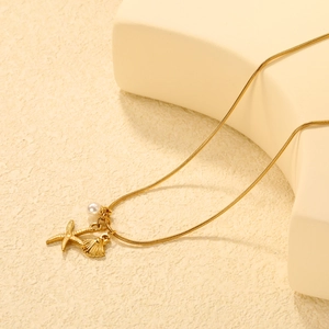 Detail of 18K gold starfish and shell pendants with white pearl on snake chain