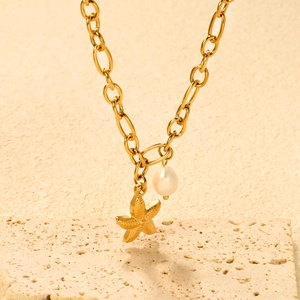 Close-up of golden sea star pendant and white pearl charm on chunky snake chain necklace