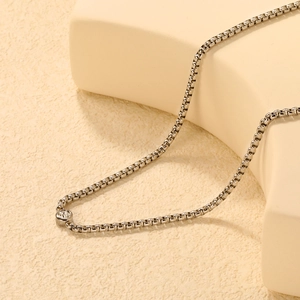 Elegant stainless steel necklace with a single round diamond pendant on a beige stand