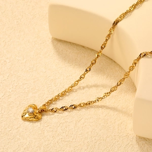 Macro shot of 18K gold plated heart necklace featuring clear zircon stone and wave chain