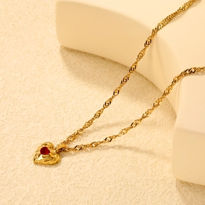 18k gold plated stainless steel necklace with red lava heart pendant on beige pedestal