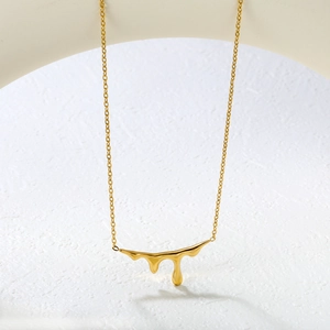Collana minimalista con goccia di lava dorata su supporto geometrico bianco