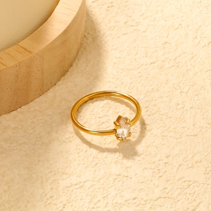 Elegante anello d'oro con zircone marquise e fascia minimalista in acciaio su fondo beige