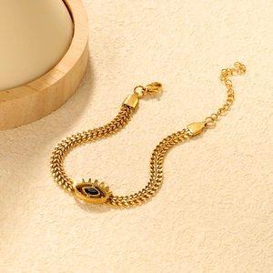 Close-up of 18K gold plated evil eye pendant with blue gem on chain bracelet