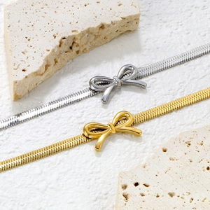 Elegant gold and silver bow snake chain bracelets on stone minimalist design