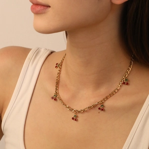 Fashionable golden stainless steel necklace with sparkling red cherry pendants worn by model