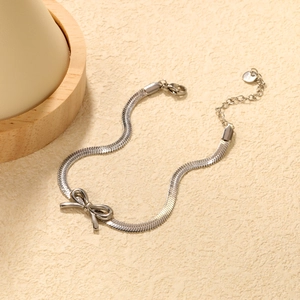 Detail view of silver snake chain bracelet featuring a bow charm and lobster clasp