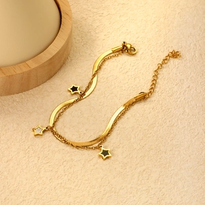 Detail of gold-plated double-layer bracelet with star pendants and sleek snake chain