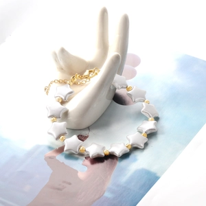 Macro view of gold snake chain bracelet featuring star-shaped mother-of-pearl charms