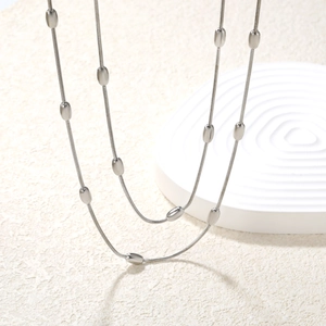 Dettaglio macro della catena a serpente argento con perline ovali lucide e stile minimal
