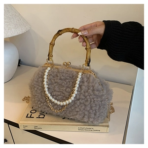 Detail of gray faux shearling handbag featuring a bamboo handle and pearl chain strap