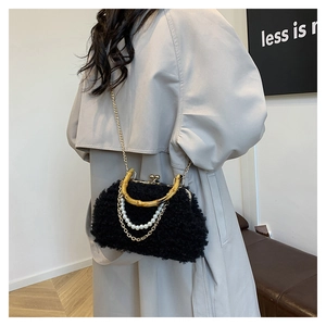 Model wearing black faux fur shell bag with bamboo handle and gold chain detail