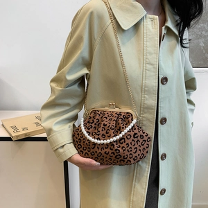 Vintage leopard shell bag with pearl handle and gold chain strap worn by a model