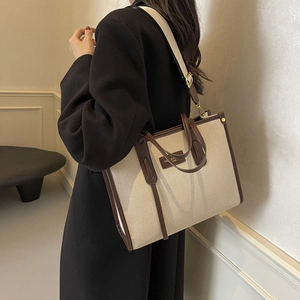 Large canvas tote bag with brown leather trim and adjustable strap for women commuting