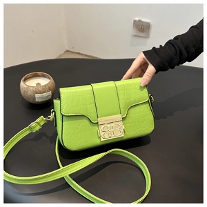 Detail der grünen Crossbody-Tasche mit Krokoprägung, goldener BB-Schnalle und Lederriemen
