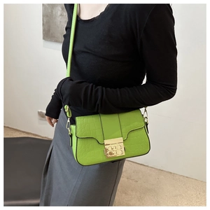 Detailaufnahme der hellgrünen kleinen quadratischen Tasche mit Krokoprägung und Goldschloss