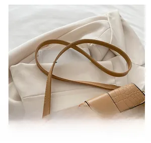 Nahaufnahme einer braunen Kroko-Lederhandtasche mit einer goldenen quadratischen Schnalle
